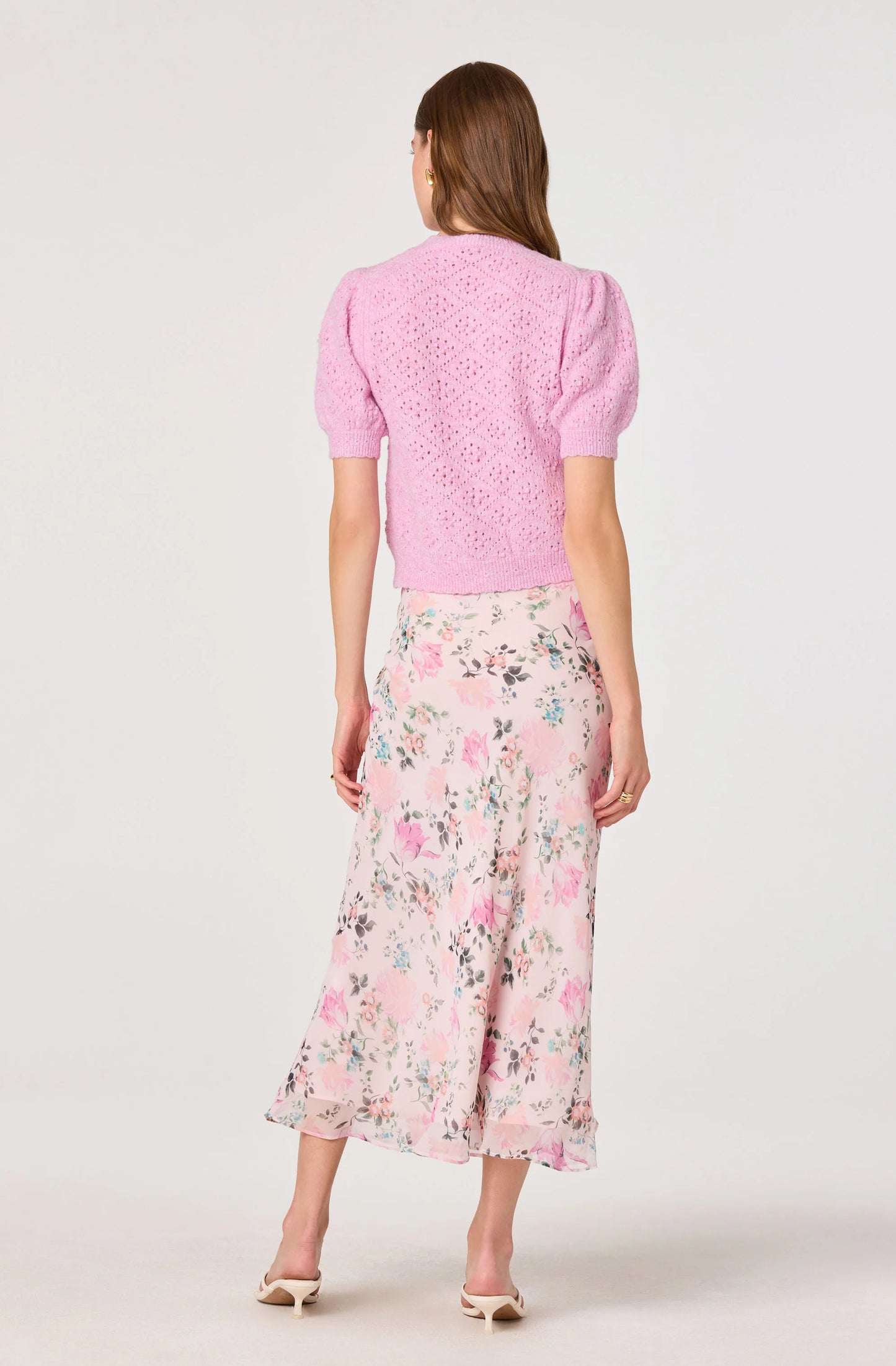 Model wearing the Ananda Floral Bias-Cut Ruffle Midi Skirt from the back, showing the blush floral print, lined midi shape, and fluid drape.