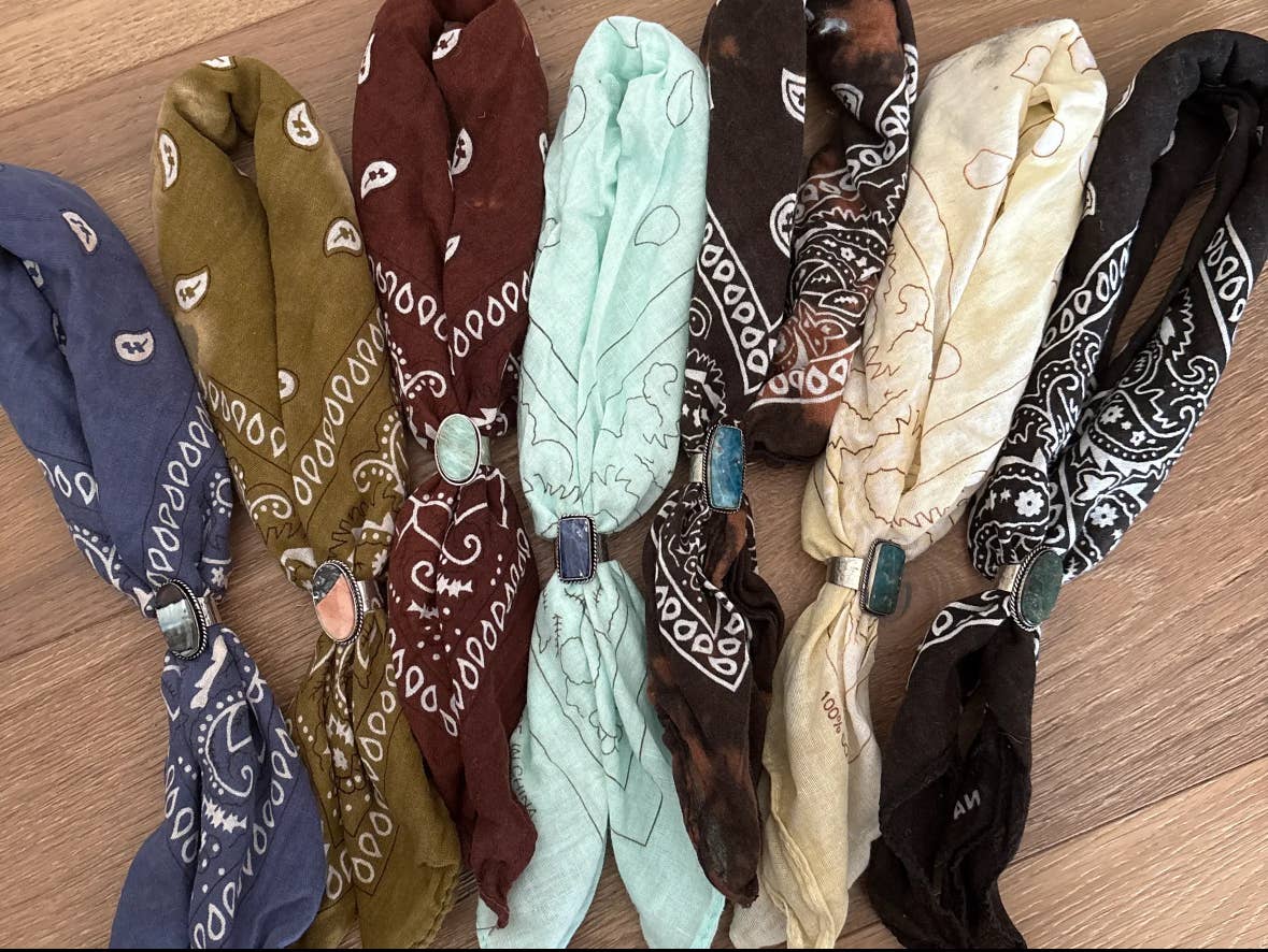 Assorted hand-distressed cotton bandanas in blue, olive, burgundy, mint, brown, cream, and black, each styled with a removable semi-precious stone slider. Crafted from 100% cotton with unique dyed and bleached patterns, showcasing the artisanal bohemian aesthetic of Stitch and Stone.
