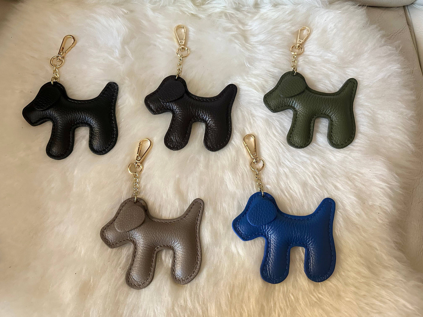 Collection of genuine leather dog-shaped keychains made in Italy, featuring the Blue 5 variant with gold-tone hardware among other available colors.