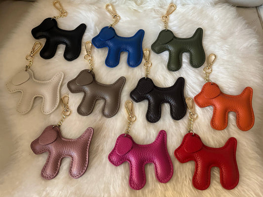 Dog-shaped genuine leather keychains in assorted colors, including the Pink 7 variant in bright pink leather with a light gold-tone clasp and chain.