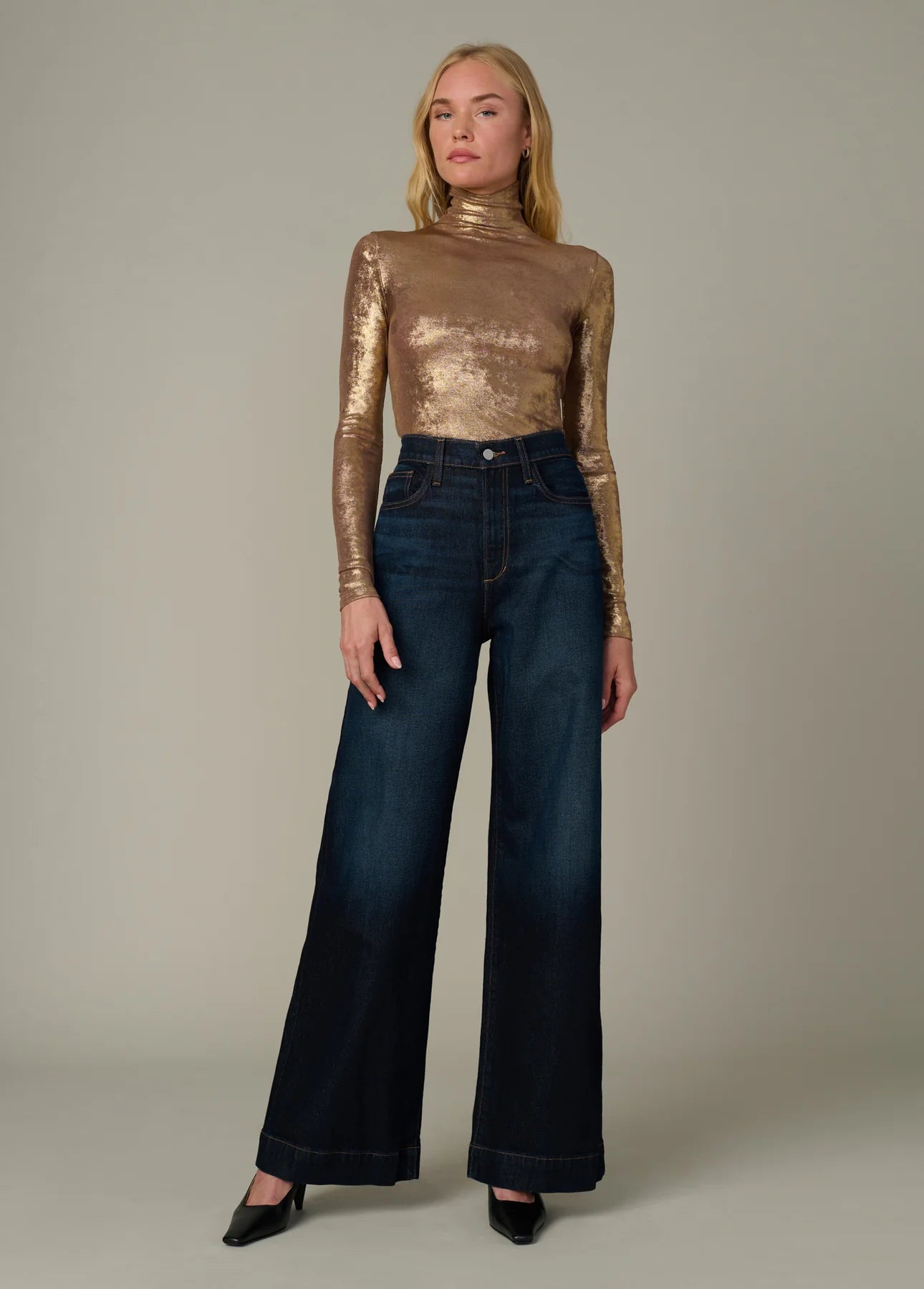 Full-body front view of the Tony Top in metallic gold featuring a fitted silhouette, funnel neckline, and long sleeves styled with dark wide-leg denim.