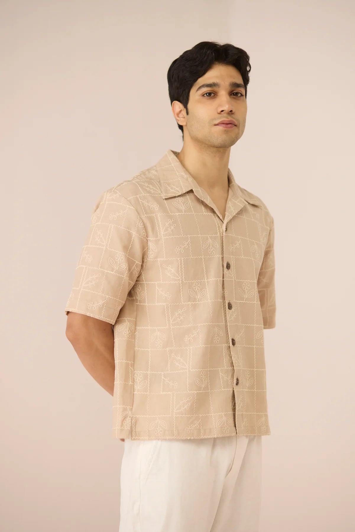 Male model wearing the Aiden Shirt in beige cotton linen with subtle grid embroidery, shown from the front at a slight angle.