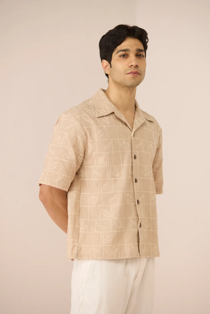 Male model wearing the Aiden Shirt in beige cotton linen with subtle grid embroidery, shown from the front at a slight angle.