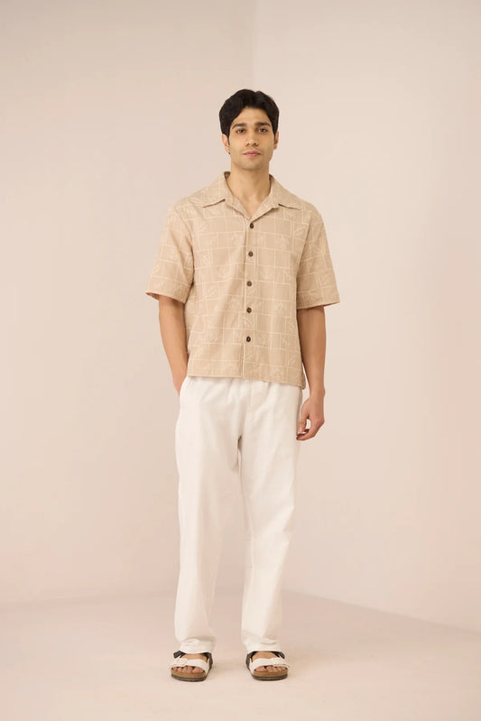 Full-length view of male model wearing the Aiden Shirt with white trousers, showing its relaxed short-sleeve silhouette.