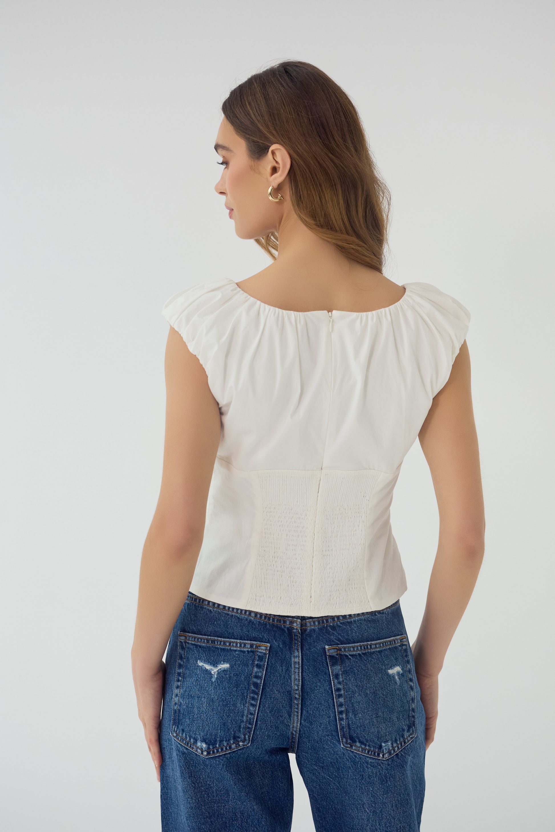 Aiko V-Neck Top in white, back view showing smocked panel and zipper closure