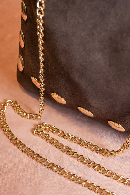 Close-up of the removable gold chain strap and studded trim on the chocolate suede Alexane Bag.