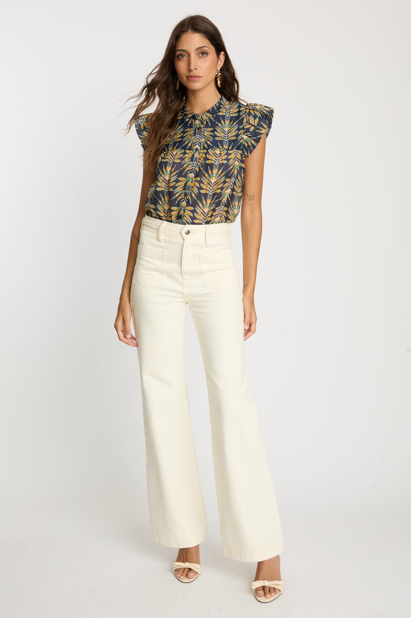 Full-length view of the Anthea Top in Deco Plume paired with cream wide-leg pants, featuring a yellow tropical leaf print and flutter sleeves.