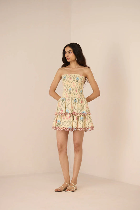 Model wearing the Apricot Mini Dress, a strapless cotton mini dress with a smocked bodice and Blue Meadow print