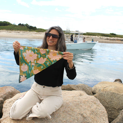 Woman holding the April Showers silk scarf outdoors by the water, showing the floral print and earthy tones.