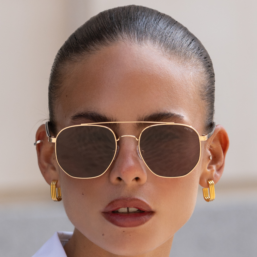 Model wearing the Austin Unisex Sunglasses in gold with brown lenses for an easy everyday look.