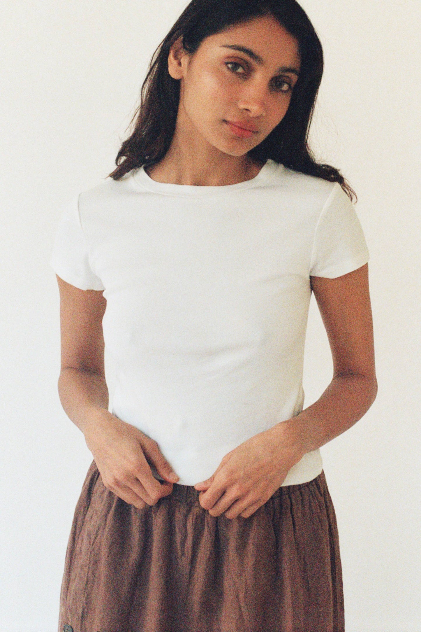Model wearing the fitted Bebe Organic Teen Tee in White paired with relaxed brown trousers.