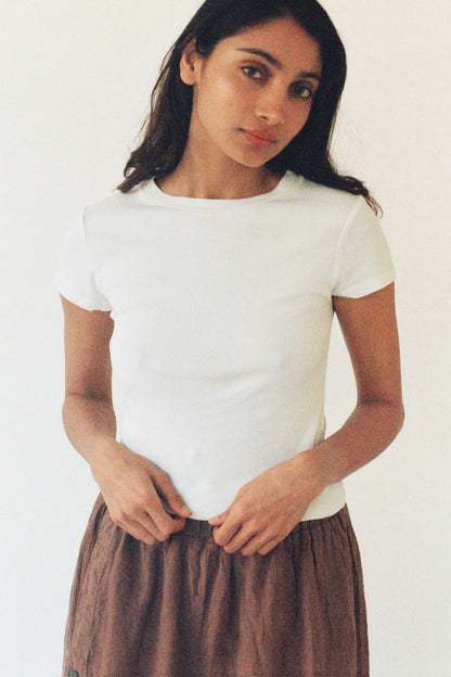 Model wearing the fitted Bebe Organic Teen Tee in White paired with relaxed brown trousers.