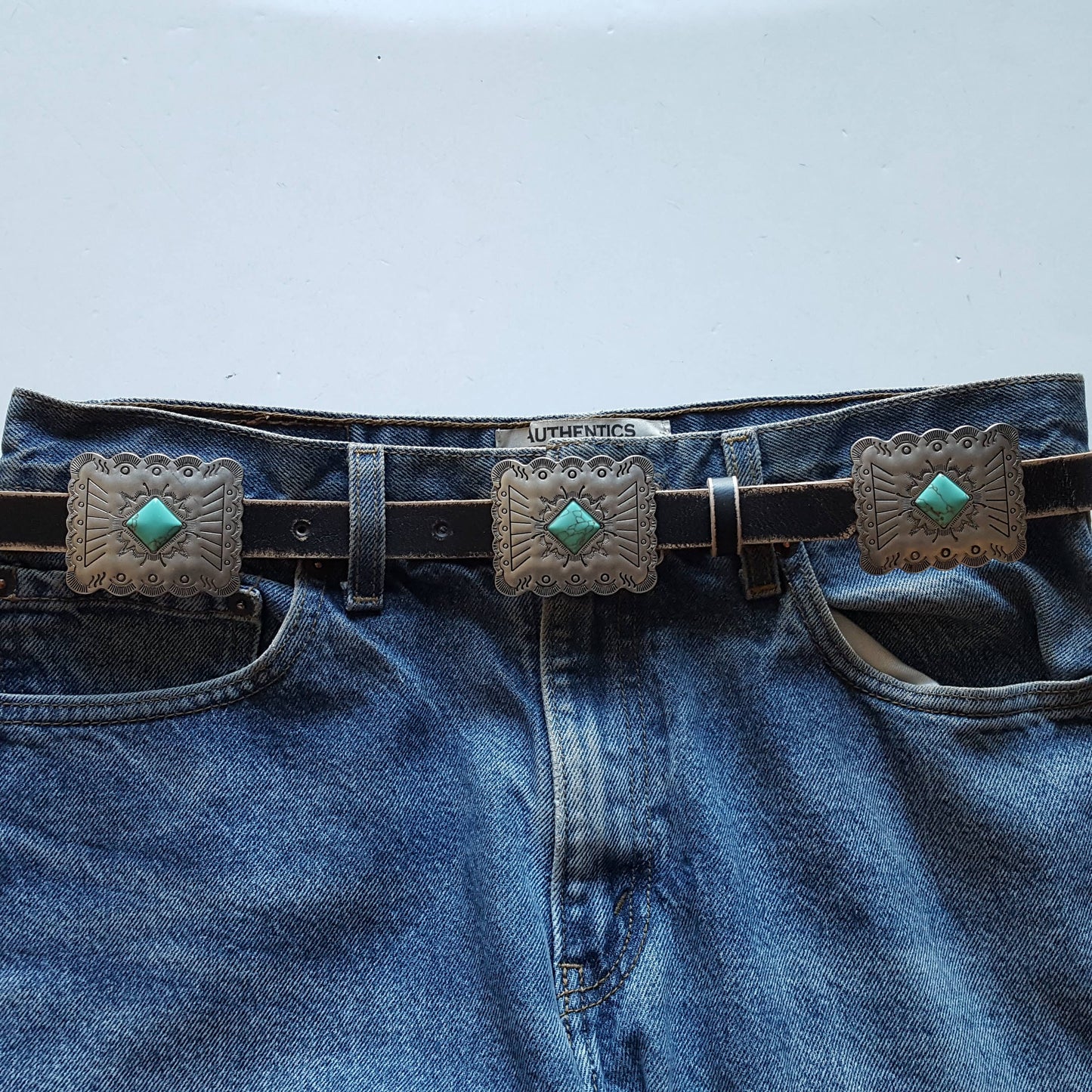 Front view of black Western genuine distressed leather belt with rectangular silver conchos and turquoise-inspired stone detailing