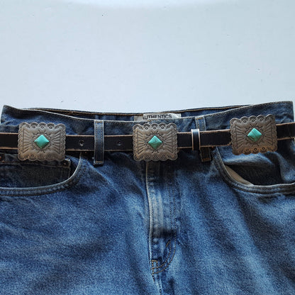 Front view of black Western genuine distressed leather belt with rectangular silver conchos and turquoise-inspired stone detailing