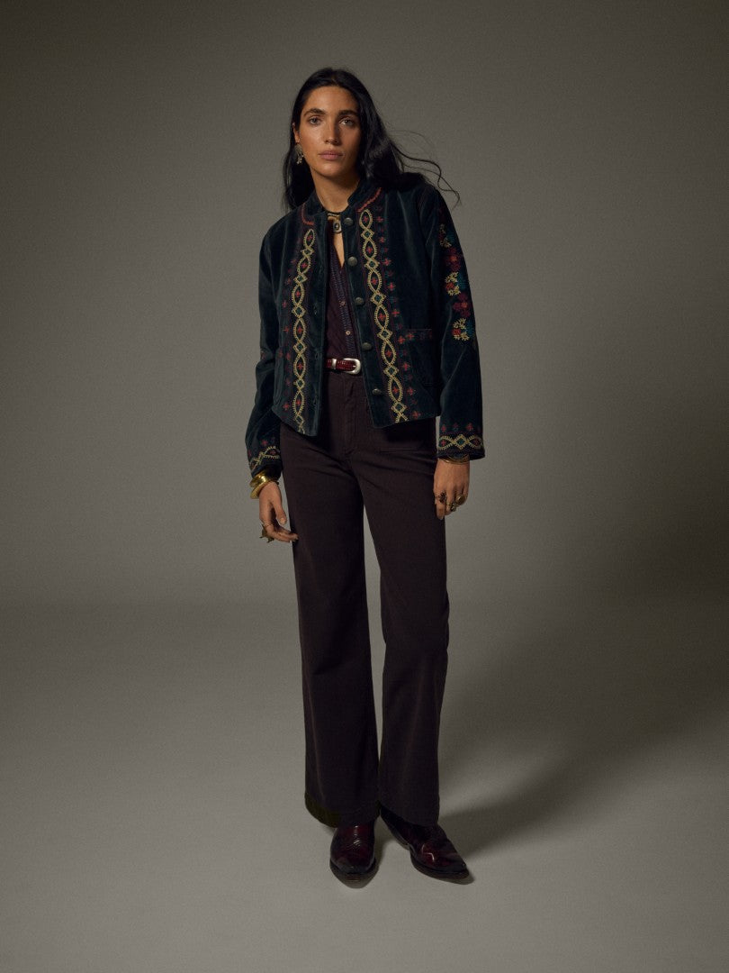 Model wearing the Breton Jacket, a cotton velvet jacket with floral embroidery, paired with dark trousers.