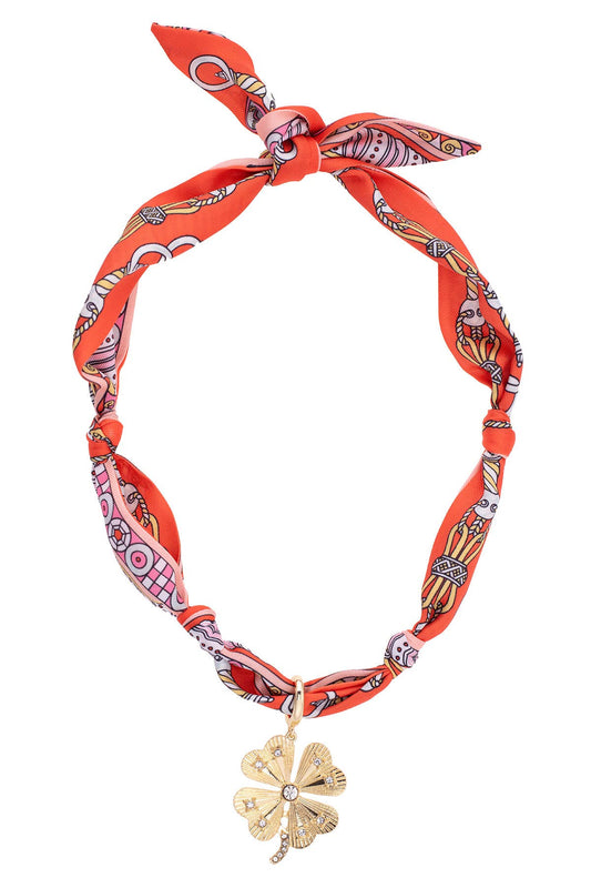 Briar Pave Clover Scarf Necklace featuring a coral, light pink, and white patterned scarf necklace with a gold-tone pavé clover charm on a white background.