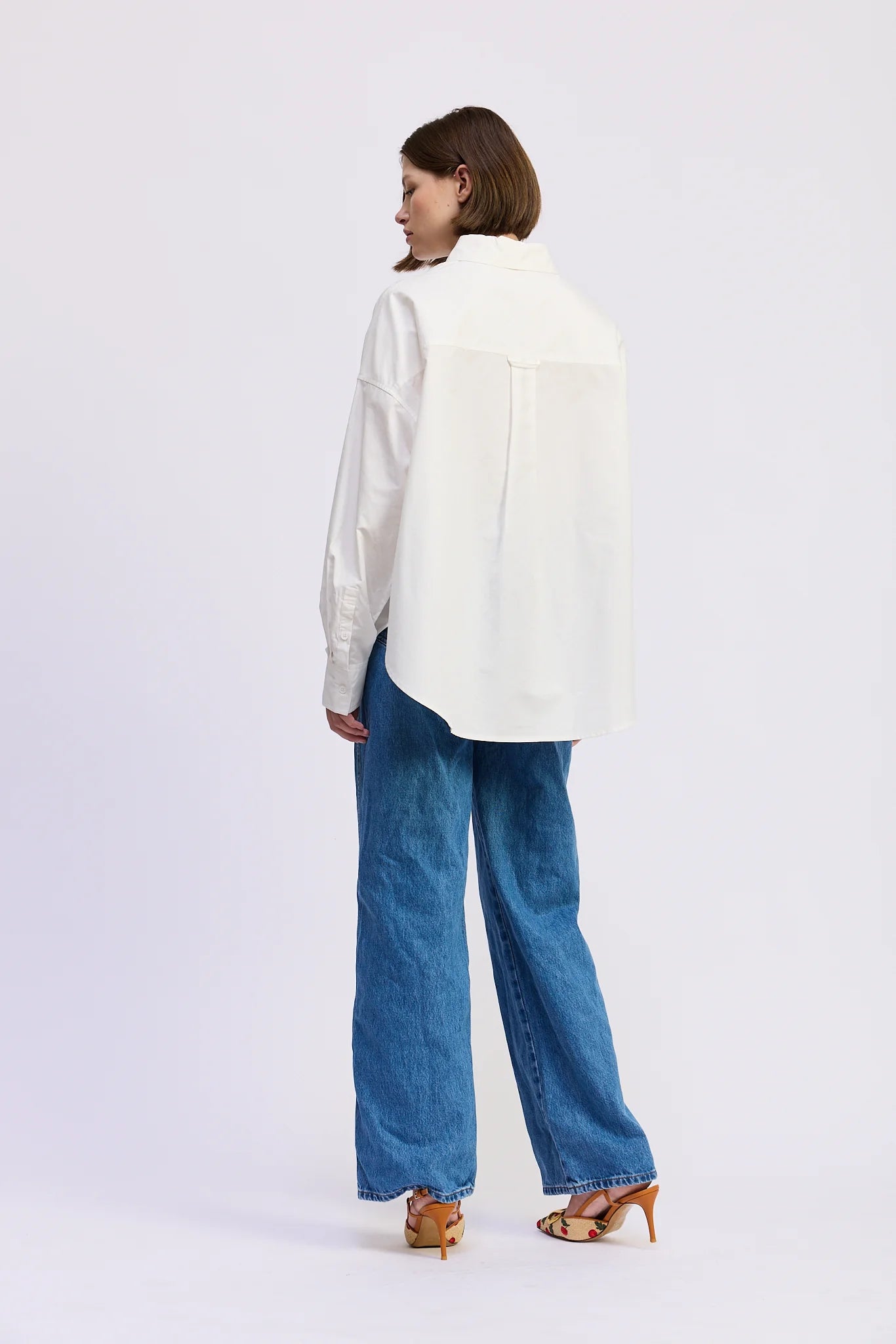 Back view of the Brittany Oversized Shirt in white with oversized silhouette and curved hem