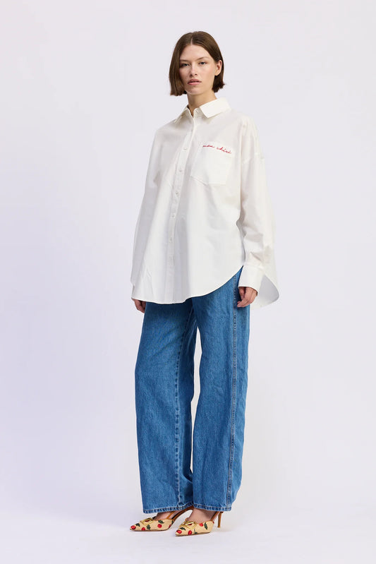 Model wearing the Brittany Oversized Shirt in white with relaxed blue jeans and printed heels