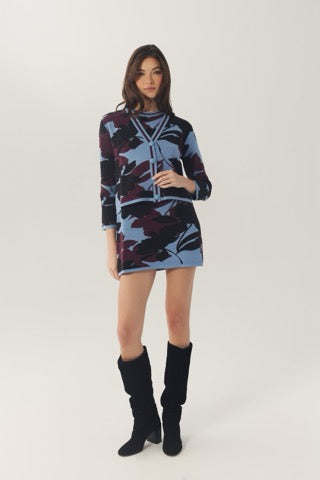 Model wearing the relaxed-fit Brook Cardigan with a coordinating floral knit dress and hands in the cardigan pockets.