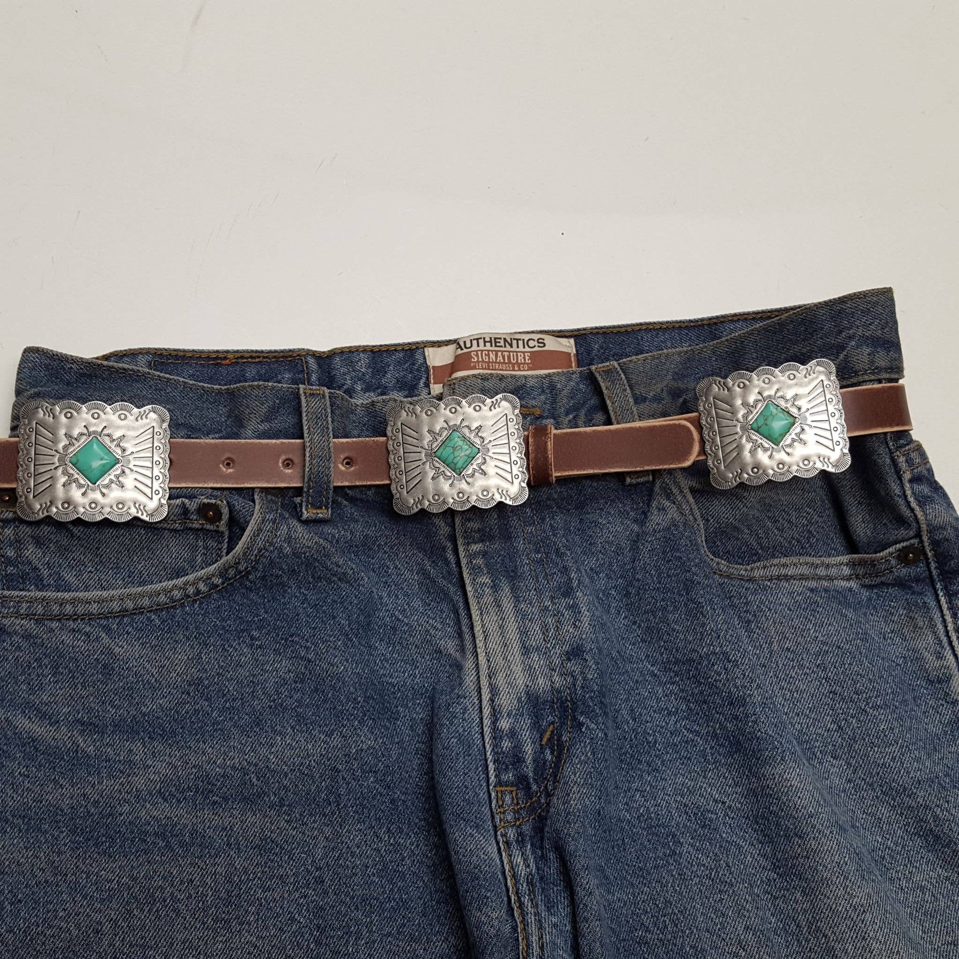 Front view of brown Western genuine distressed leather belt featuring engraved rectangular conchos and matching silver hardware