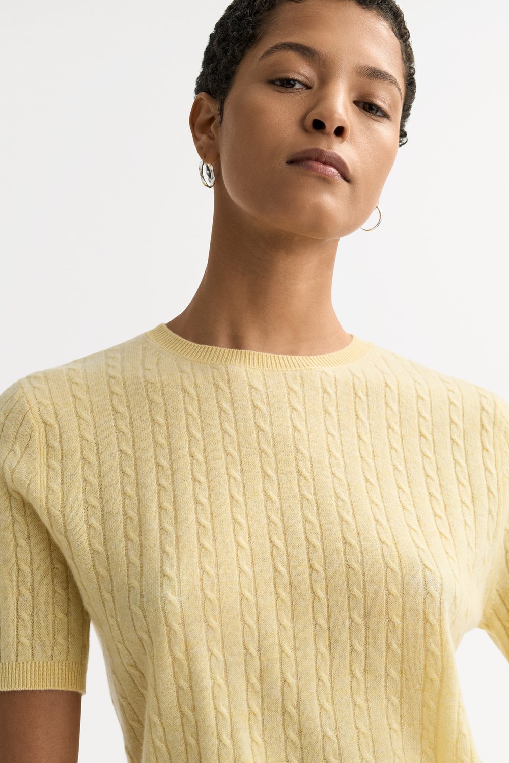 Close-up detail of the honeydew yellow cable knit cashmere top showing the textured knit pattern and crew neckline