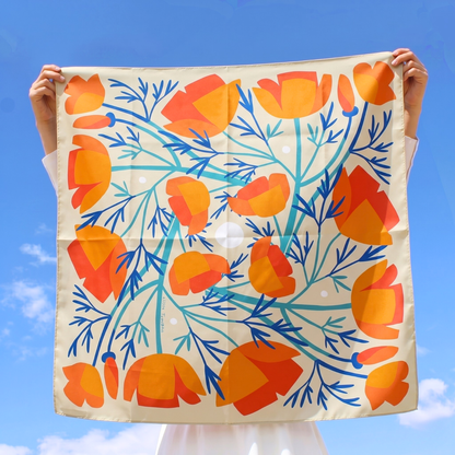 California Poppies silk scarf held up outdoors against a bright blue sky, showing the full orange poppy print.