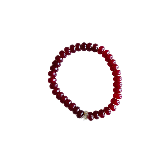 Handmade maroon jade stretch bracelet with glossy gemstone beads and a pave spacer bead on a white background.