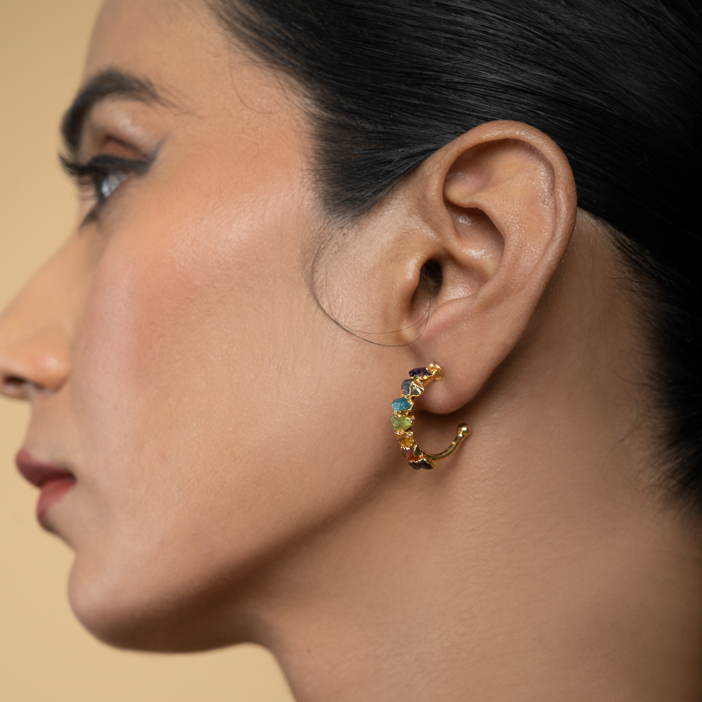 Model wearing colorful natural stone chakra hoop earrings in a side-profile view.