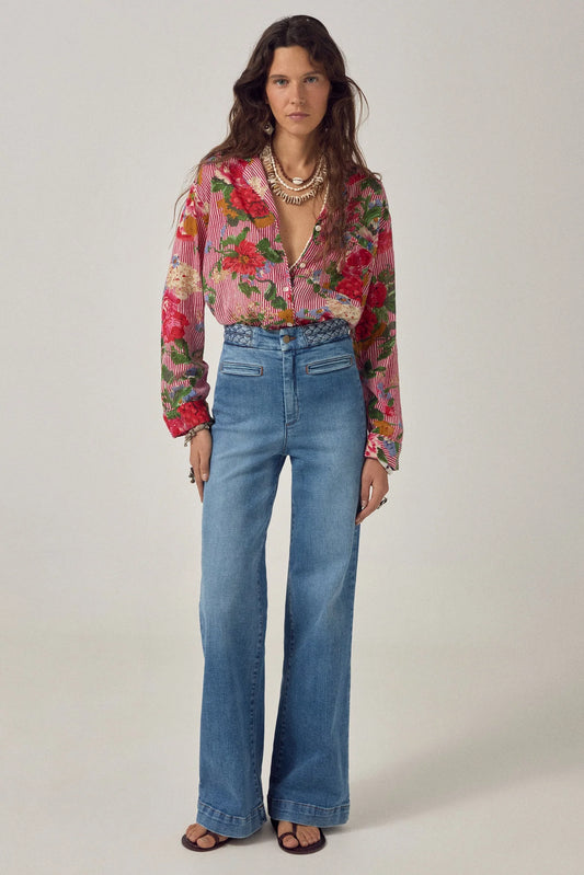 Model wearing Cher Pant in Braid Denim featuring a braided waistband, high-rise fit, and softly flared wide-leg silhouette paired with a floral blouse.