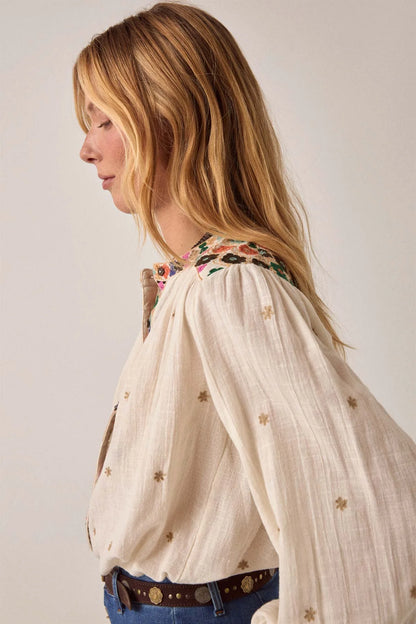 Side profile of the Cleo blouse in off-white featuring gathered shoulders, colorful embroidery along the yoke, and an airy relaxed silhouette.