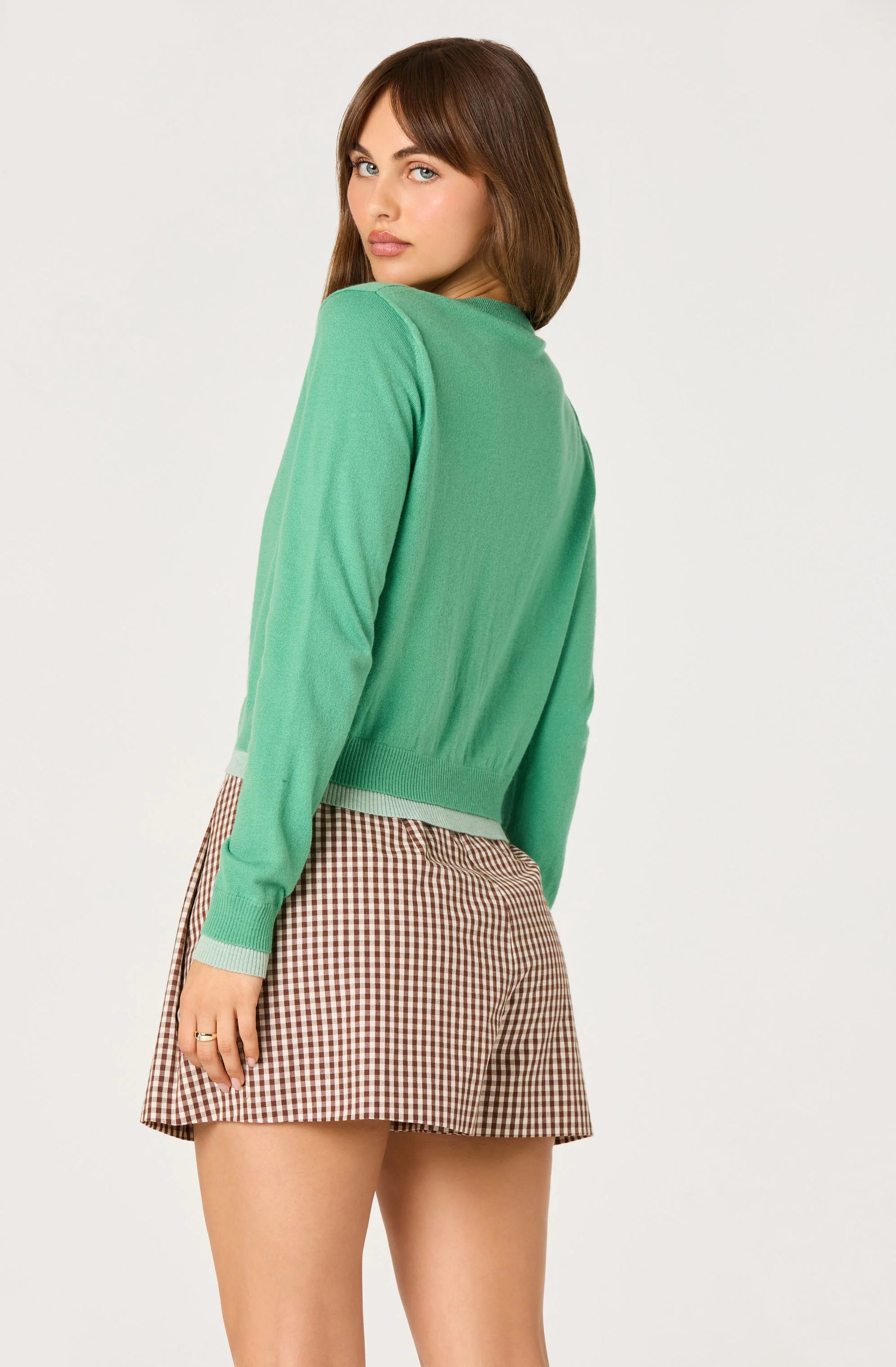 Back view of the Clovis Color Block Faux Layered Cardigan showing the green knit body, long sleeves, and light contrast ribbed hem.