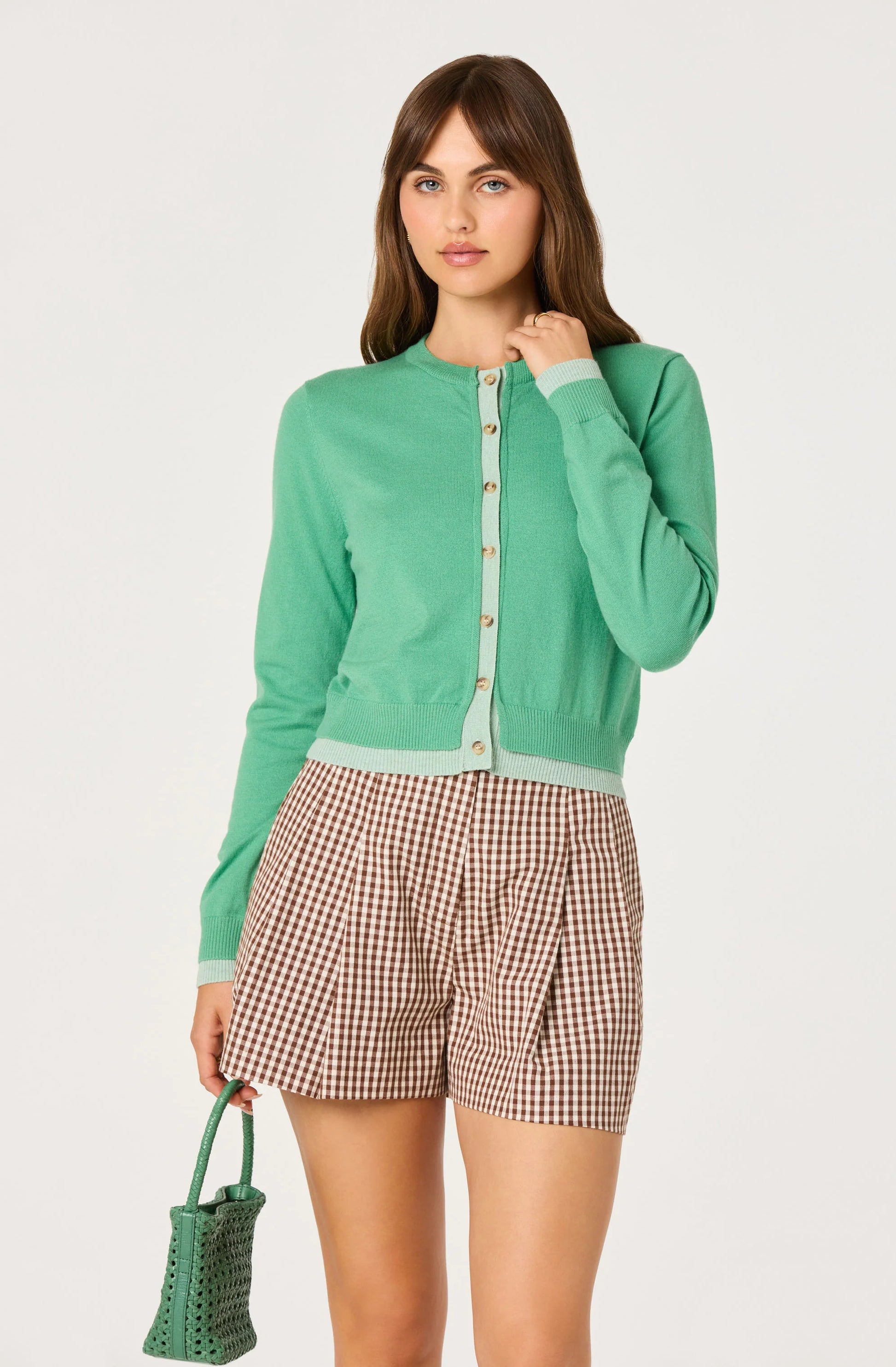 Model wearing the Clovis Color Block Faux Layered Cardigan in green with light contrast trim, button-front closure, and ribbed hem.