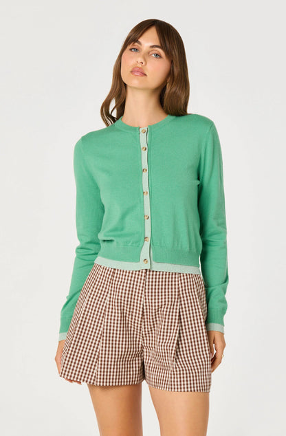 Model wearing the Clovis Color Block Faux Layered Cardigan with gingham shorts, showing the round neckline, long sleeves, and button-front closure.