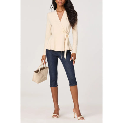 Model wearing the Dayna cream knit wrap top with dark denim capri jeans, neutral heels, and a woven handbag