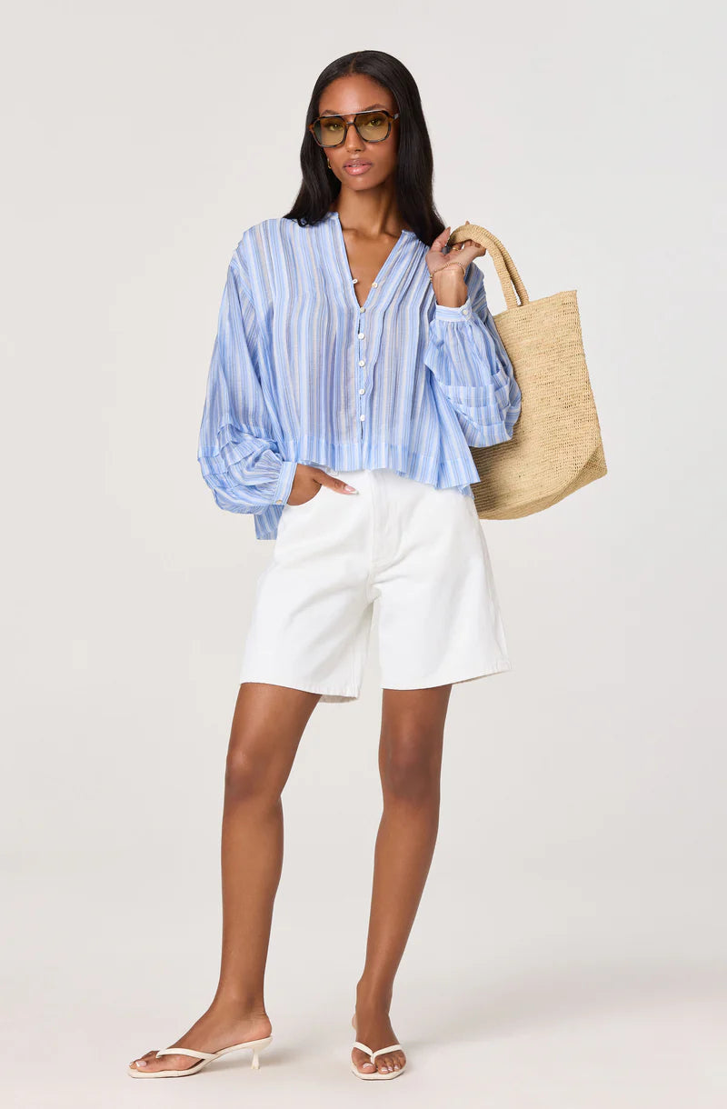 Model styling the Ericka Top in blue stripe with white shorts and a woven tote bag