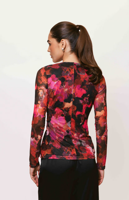 Back view of the Evia Top showcasing the vibrant red, pink, and black abstract floral print on stretch mesh fabric with fitted long sleeves.