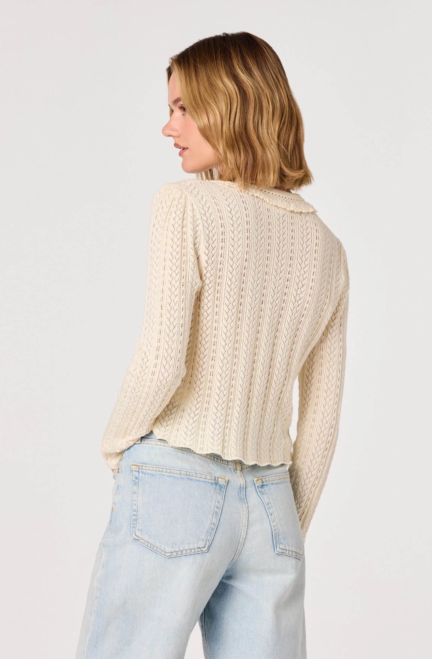 Back view of the cream Fannie Cardigan highlighting the delicate open-knit texture and lightweight long sleeve silhouette.