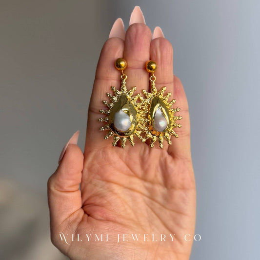 Fire Pearl Statement Earrings with gold-tone detailing and luminous pearl centers displayed on hand