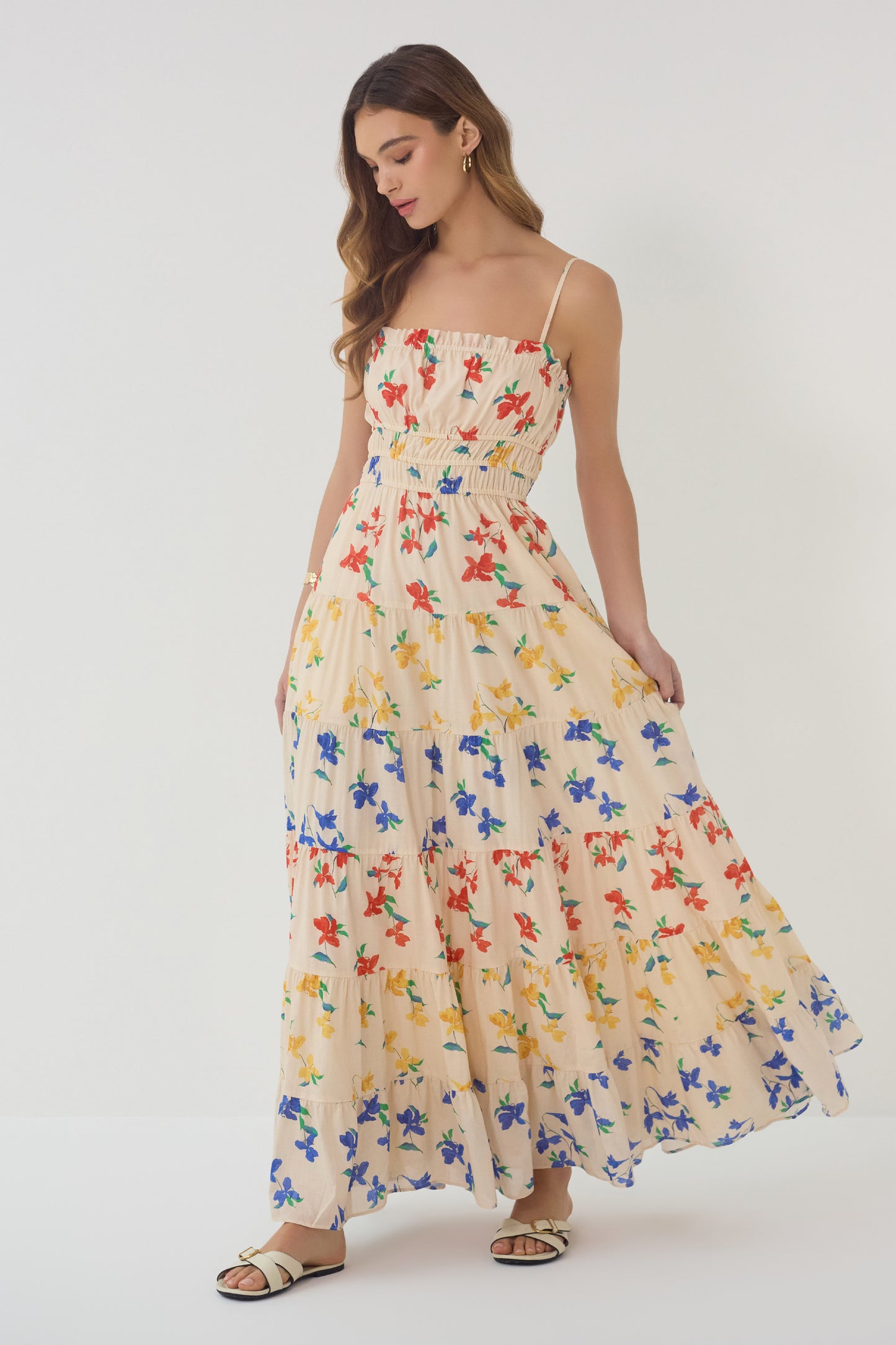 Model holding Flynn Dress showing flowy tiered skirt and lightweight floral fabric in red blue and yellow print