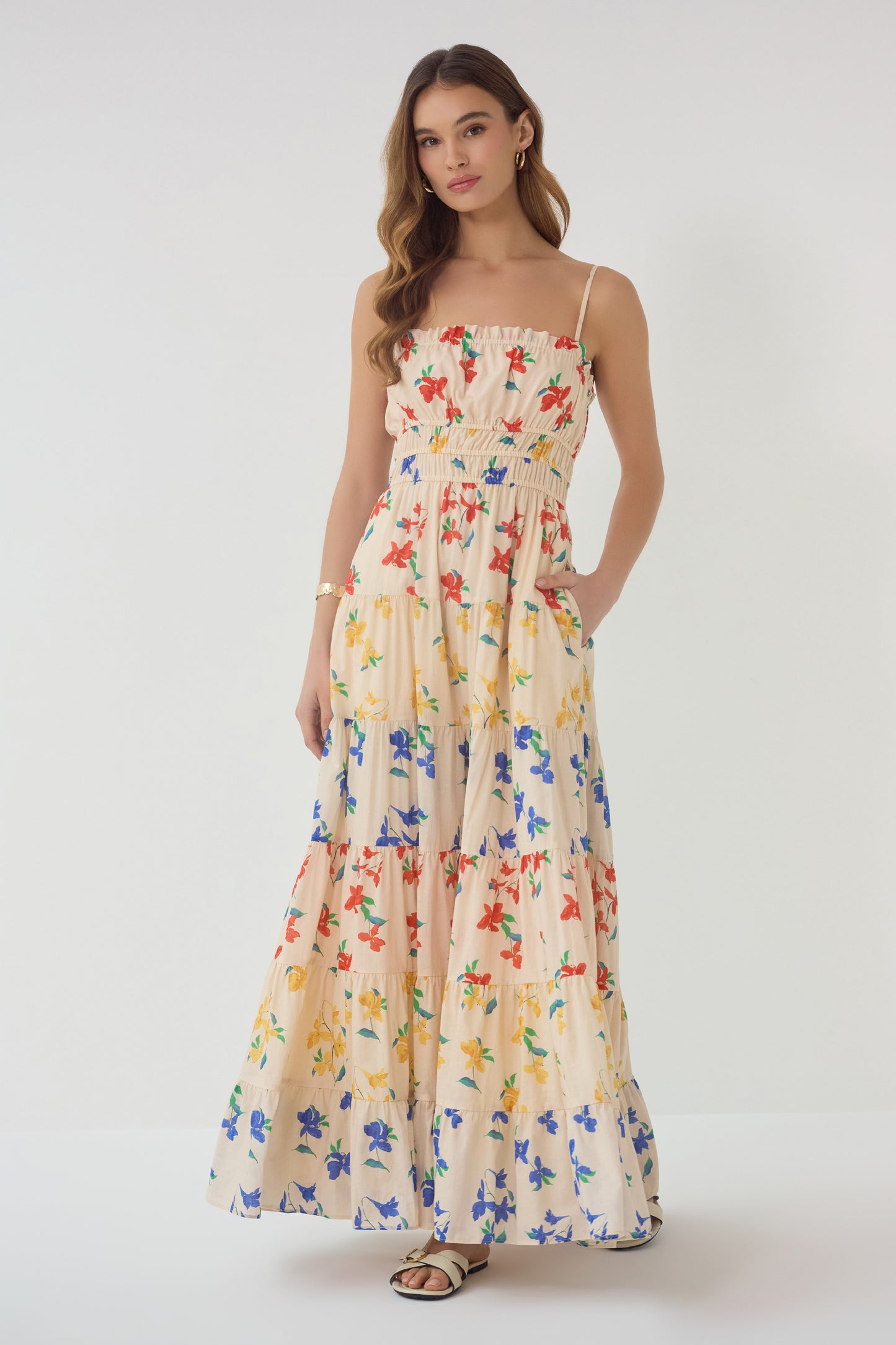 Model wearing Flynn Dress in red blue yellow floral print with smocked bodice and tiered maxi skirt front view