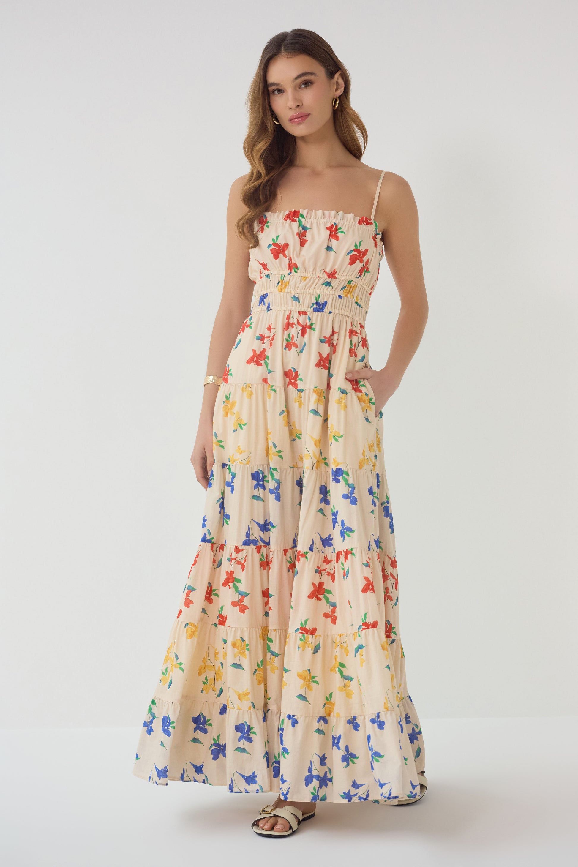 Model wearing Flynn Dress in red blue yellow floral print with smocked bodice and tiered maxi skirt front view