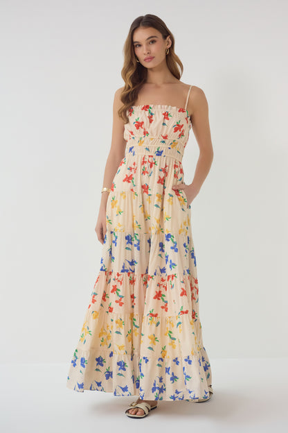 Model wearing Flynn Dress in red blue yellow floral print with smocked bodice and tiered maxi skirt front view