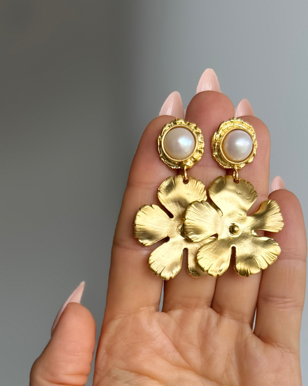 Full Bloom freshwater pearl earrings with 8mm pearls and sculptural 24k gold-filled floral drops held in hand.