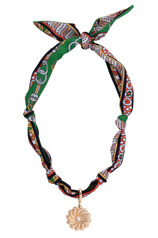 Green, black, and orange printed scarf necklace with gold flower pendant and pearl center detail.