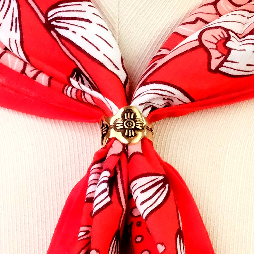 Close-up of the Gladys Brass Bandana Slide Ring holding a red patterned bandana in place.
