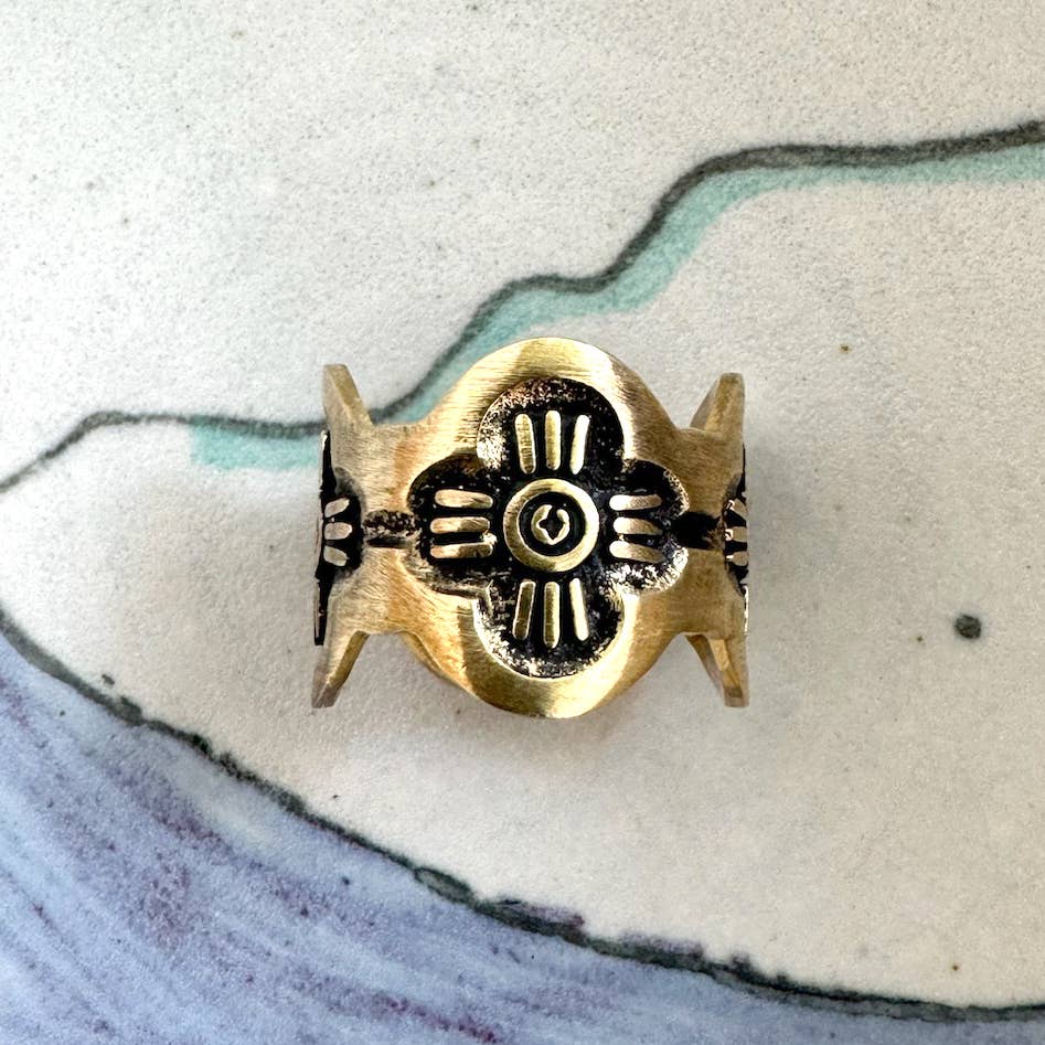 Close-up of the Gladys Brass Bandana Slide Ring with petite floral artwork displayed on a ceramic surface.