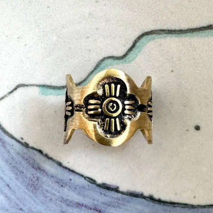Close-up of the Gladys Brass Bandana Slide Ring with petite floral artwork displayed on a ceramic surface.