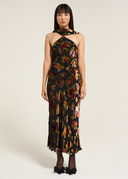 Model wearing the Hayley Dress in Countryside Devoré Black featuring a halter-neck silhouette, metallic floral devoré pattern, and flowing black maxi skirt.