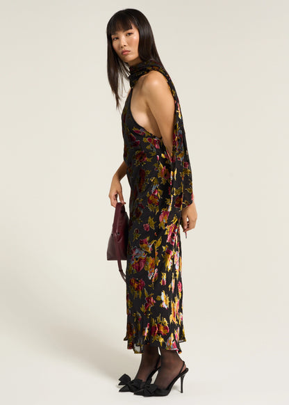 Side styled view of the Hayley Dress in Countryside Devoré Black featuring a halter neckline, open sides, and flowing floral devoré fabric.