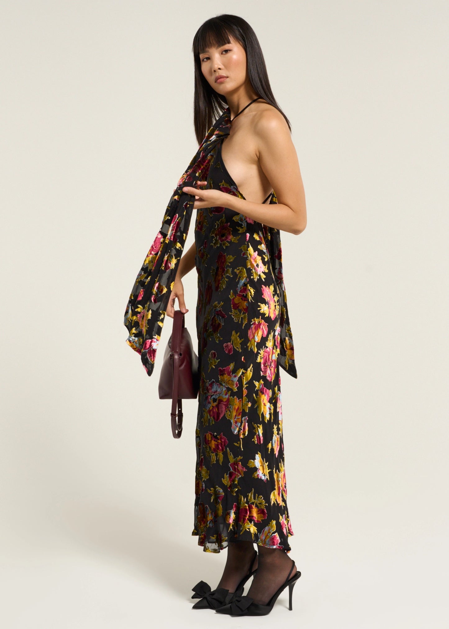 Model styling the Hayley Dress in Countryside Devoré Black with a draped scarf neckline, floral metallic pattern, and burgundy handbag.
